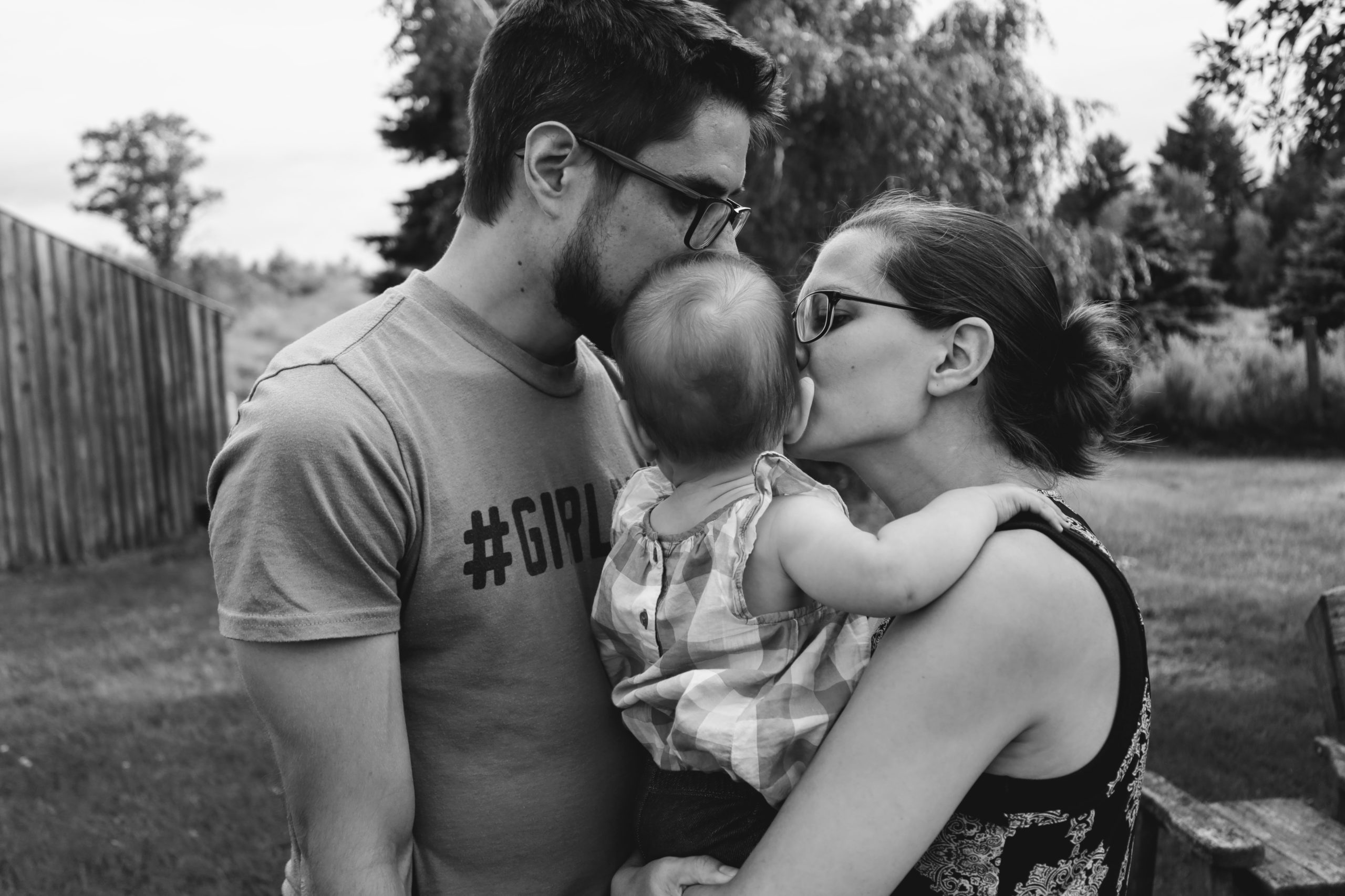 mom dad little girl mom dad kissing baby black and white